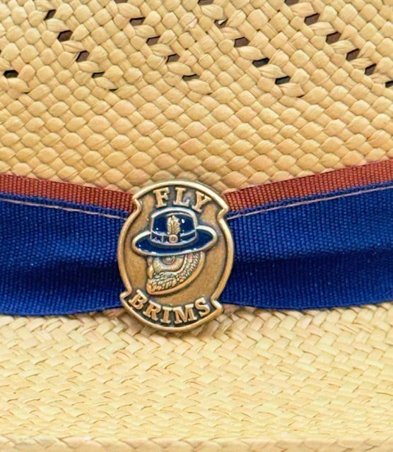 Fly Brims Toucan Crest Natural Fedora featuring a woven straw texture with a navy band and metallic logo emblem.